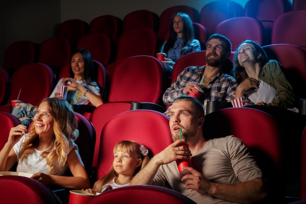 Group of friends sitting in movie theater with popcorn and drinks