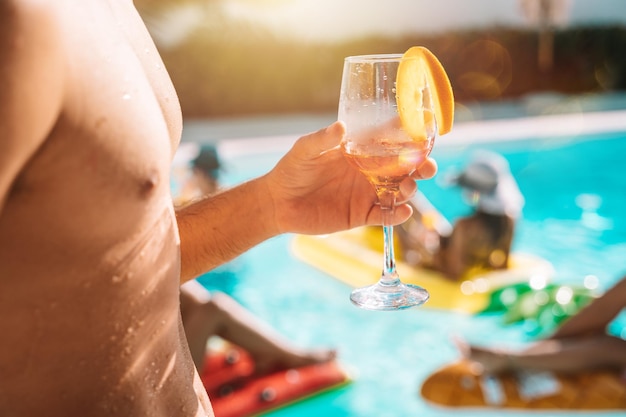 Group of friends in swimsuit drink a cocktail in a swimming pool