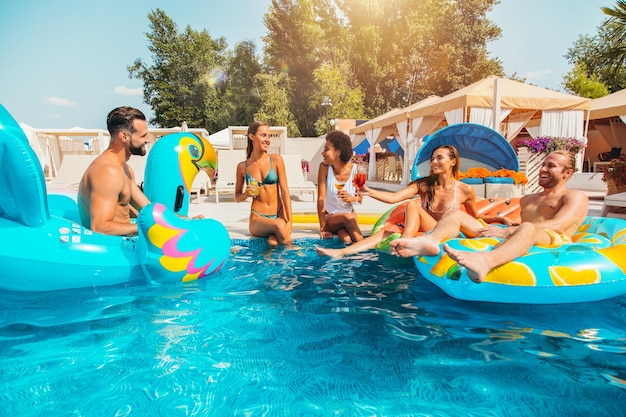 Group of friends in swimsuit enjoy in a swimming pool