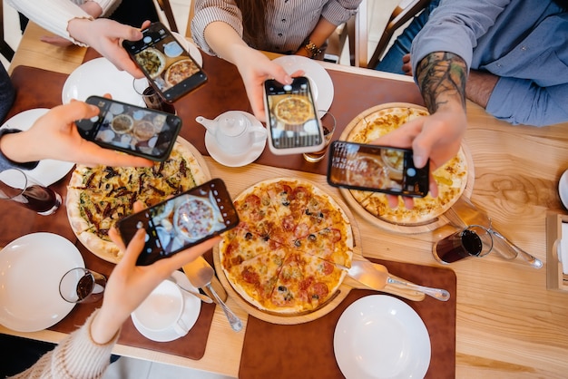 A group of friends takes a close-up photo of a delicious pizza for the blog, pizzeria.