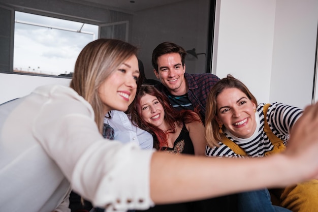 Group of friends taking a selfie at a home party and spending fun time together Concept lifestyle party together