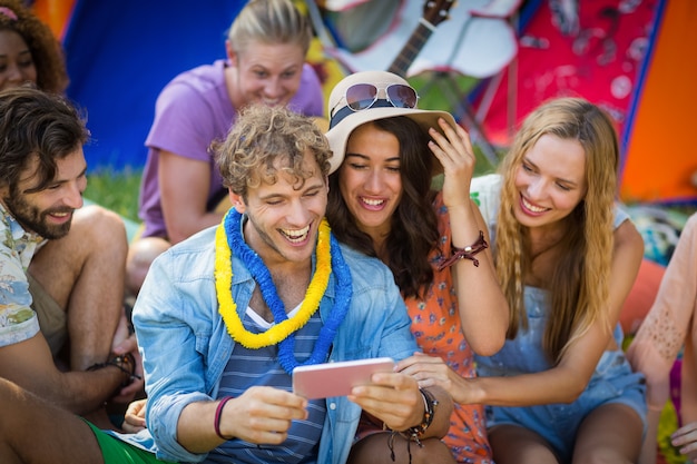 Group of friends using mobile phone at campsite