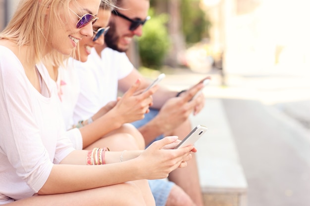 group of friends using smart phones in the city