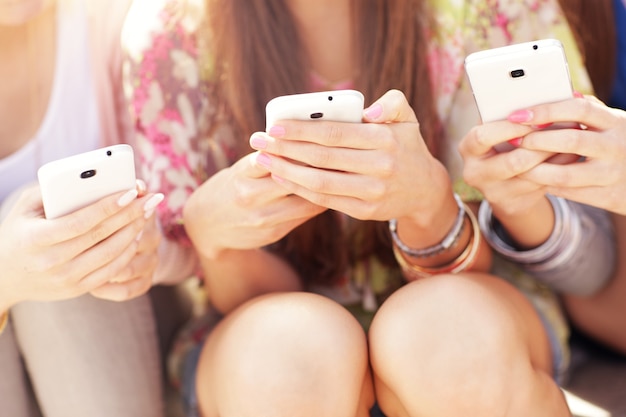 group of friends using smartphones in the city