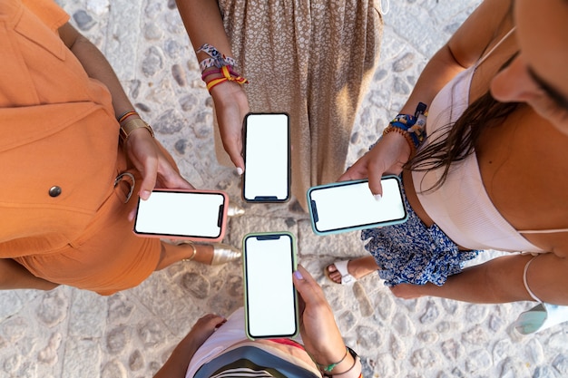 Group of girlfriends looking at their phones from above