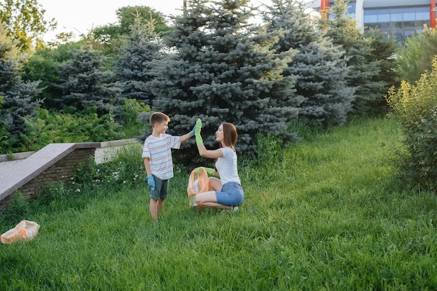 A group of girls with children at sunset are engaged in garbage collection in the park. Environmental care, recycling.