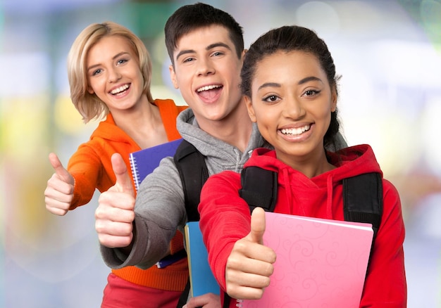 Group of graduated students with showing thumbs up on blurred background