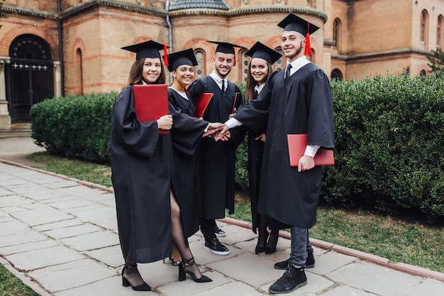 Group graduation of students looking very happy with diploma.