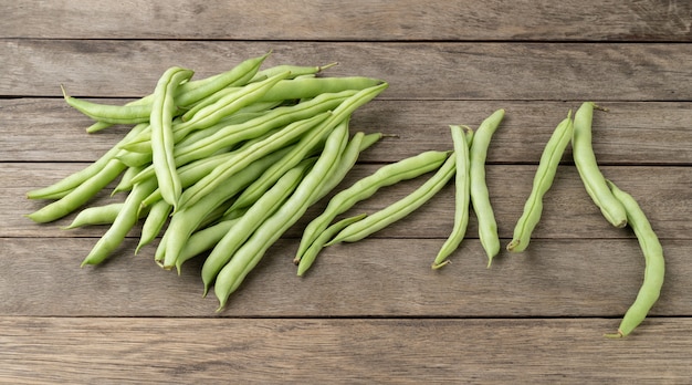 A group of green bean pods over wooden table.