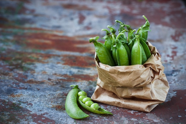 Group green peas in a paper package on a rusty table