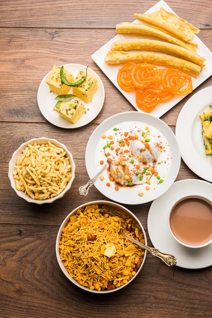 Group of Gujarati snacks like jalebi-fafda, thepla, khaman dhokla, aloo bhujiya, khandvi,khakra, dahi vada, gathiya with hot tea