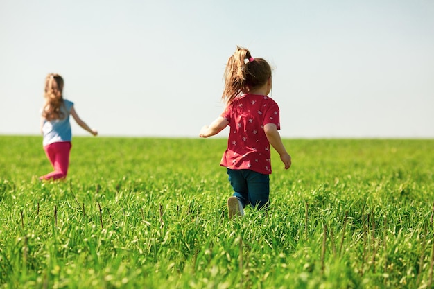 A group of happy children of boys and girls run in the Park on the grass on a Sunny summer day  The concept of ethnic friendship peace kindness childhood