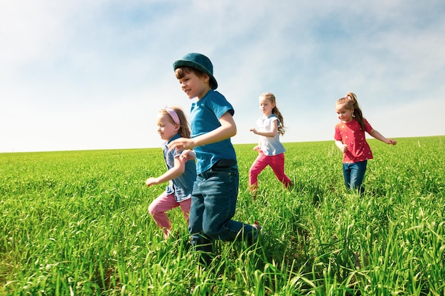 A group of happy children of boys and girls run in the Park on the grass on a Sunny summer day  The concept of ethnic friendship peace kindness childhood