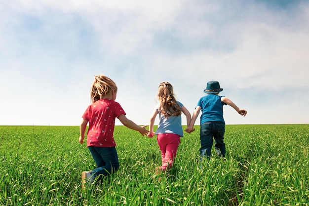 A group of happy children of boys and girls run in the Park on the grass on a Sunny summer day  The concept of ethnic friendship peace kindness childhood