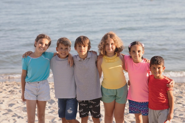 Group of happy children having fun on the beach hugging and smiling looking to the camera Kids enjoying summer holidays with friends