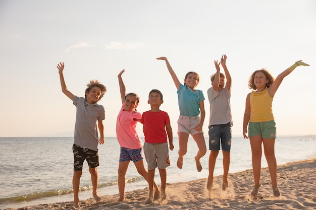 Group of happy children having fun on the beach jumping and smiling Kids enjoying summer holidays with friends