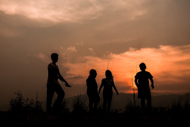 Group of happy children playing on meadow at sunset