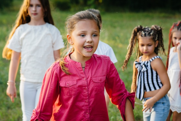 A group of happy children run and play in the Park during sunset. Summer children's camp.