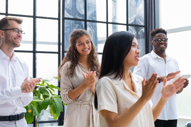 Group of happy employees standing in the office applauding