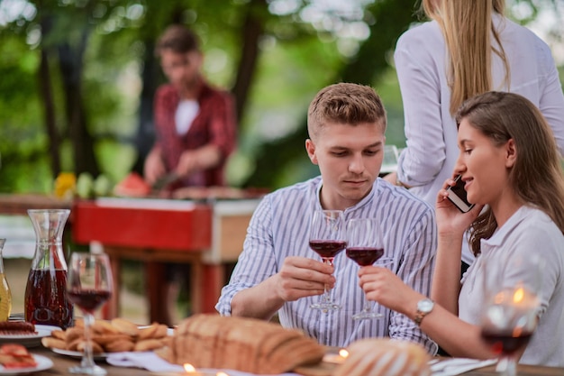 group of happy friends having picnic french dinner party outdoor during summer holiday vacation near the river at beautiful nature