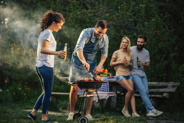 Group of happy friends making barbecue outdoors