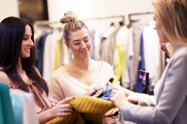 group of happy friends shopping for clothes in mall