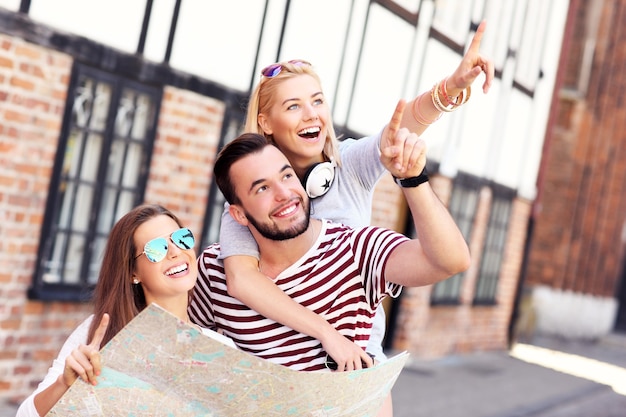 group of happy friends sightseeing Gdansk with map