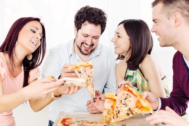 Group of happy friends sitting and eating pizza at Home Interior.