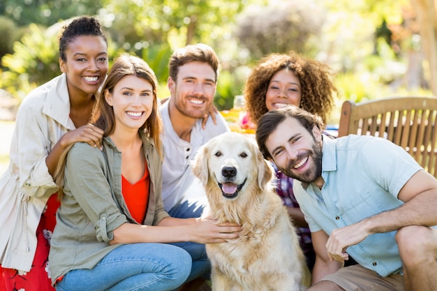 Group of happy friends sitting together with the dog