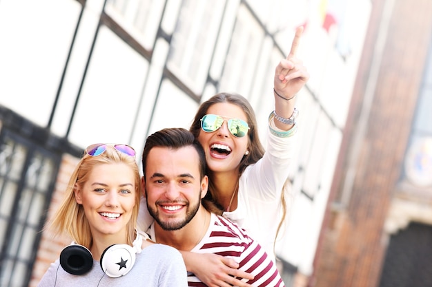 group of happy friends smiling to the camera and pointing at copy space