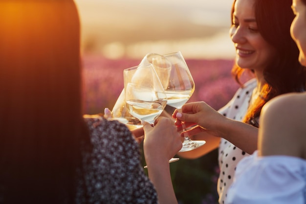 Group of happy girlfriends clinking glasses with wine