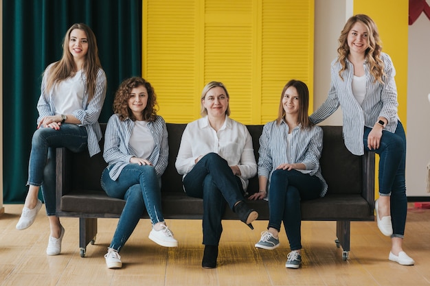 Group of happy girls posing on sofa. studio photo.