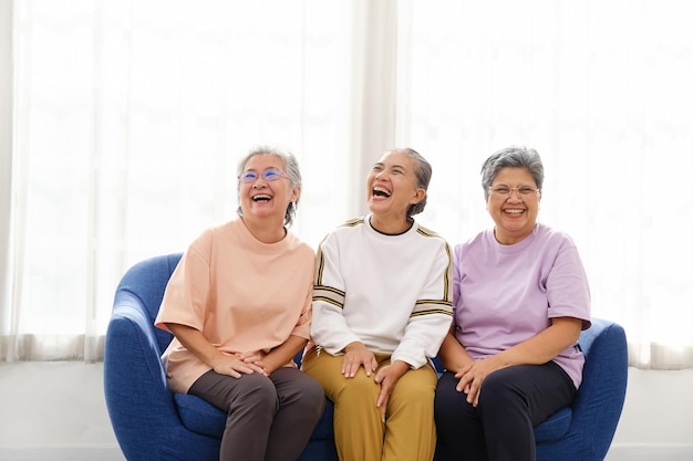 The group of happy and healthy three Asian senior women sits together on a sofa Smiling and laughing together