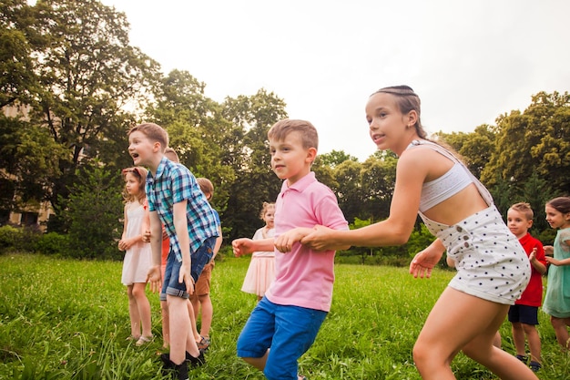 Group of happy kids playing games in summer camp. Happy friends having fun outdoors.