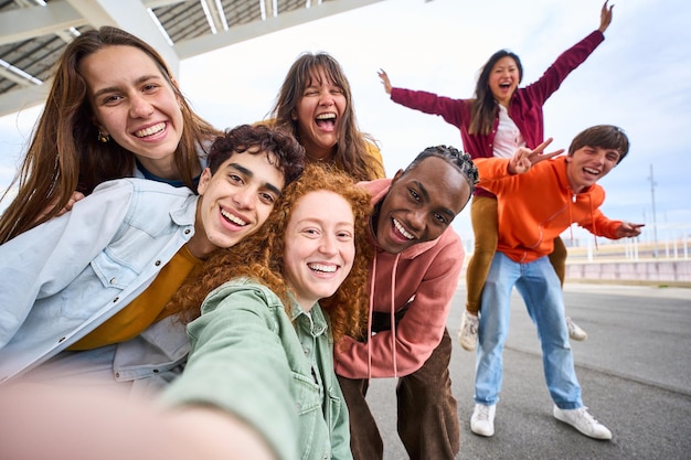 Photo group of happy multiracial friends taking a selfie photo with cell phone outside youth concept