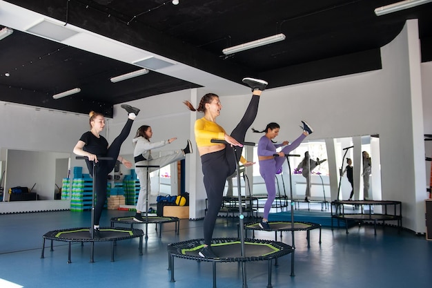 Group of happy women warming up before training in gym jumping on trampoline