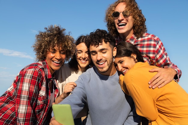 Group of happy young multiracial friends having fun take selfie together using cellphone outdoors