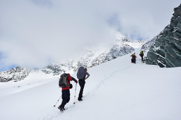 Group of hikers climbing the hill covered with snow