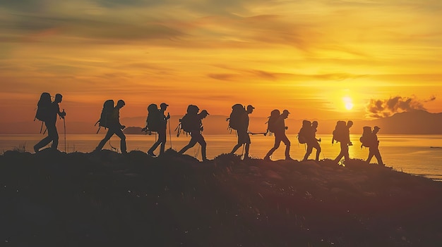 A group of hikers walk along a mountain ridge at sunset The sky is a bright orange and the sun is setting behind them