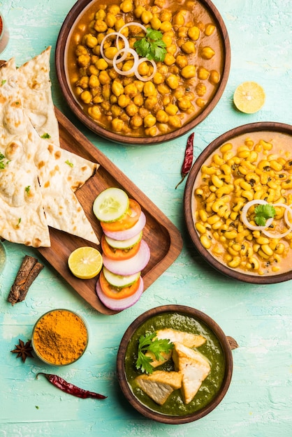 Group of Indian food like Palak Paneer Butter Masala, Choley or chola and Black Eyed Kidney Beans curry with Naan and Rice