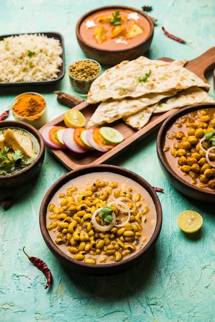 Group of Indian food like Palak Paneer Butter Masala, Choley or chola and Black Eyed Kidney Beans curry with Naan and Rice