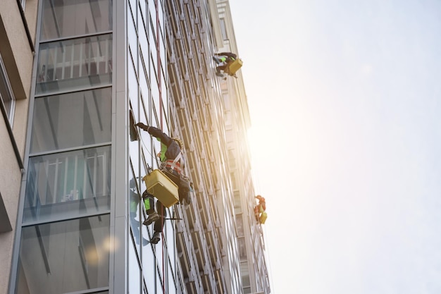 Photo group industrial mountaineering workers in uniform washing exterior building glazing