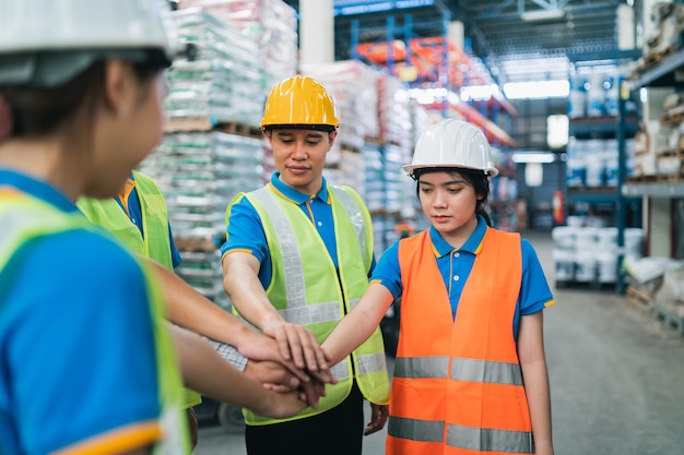 Group of industrial warehouse asian worker in safety suite hand stack celebrate successful or deal commitment Logistics supply chain and warehouse businessTeamwork unity under view concept