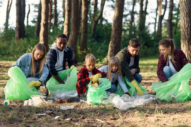 Group of international multi aged volunteers keep nature clean and picking up garbage from the forest. Ecology concept.