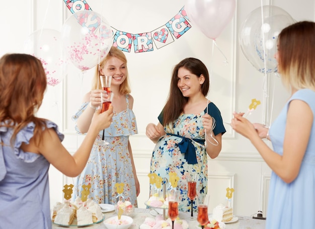 A group of a joyful women celebrating together during the genre reveal the party over balloons background