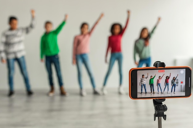 Group Of Kids Filming Video For Blog Via Smartphone Indoors