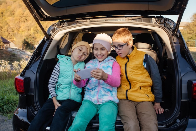 Group of kids taking selfies with smartphone sitting on the car