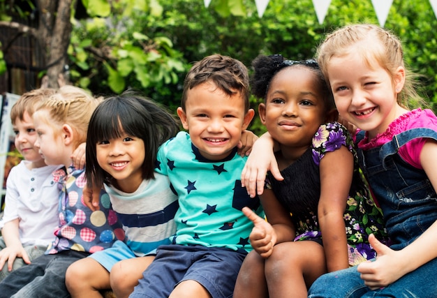 Group of kindergarten kids friends arm around sitting and smiling fun