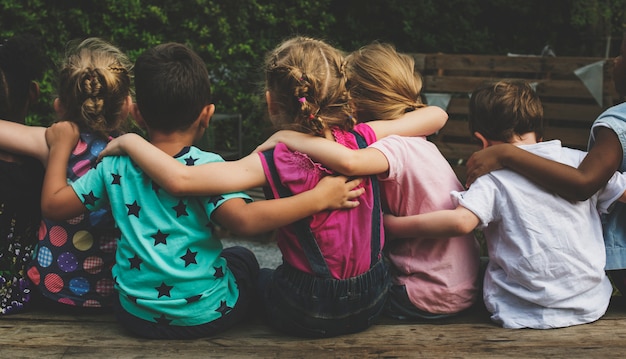 Photo group of kindergarten kids friends arm around sitting together