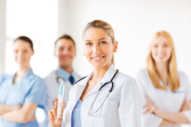 group of medics with female doctor holding syringe with injection